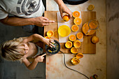 Boy making orange juice with father