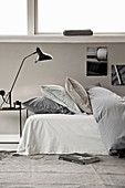 Bed with duvet and pillows, bedside table with reading lamp