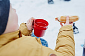 Child having hot dog and tea outside in winter