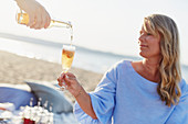 Woman with drink having picnic on beach