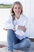 A long-haired blonde woman wearing a white shirt blouse and jeans