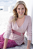 Blonde, langhaarige Frau in rosa Outfit