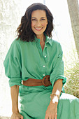 An older brunette woman wearing a green dress