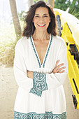 An older brunette woman wearing a white dress with a trim