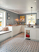 Renovierte Küche mit weißen Unterschränken, blau-grauen Wänden und Fliesenboden