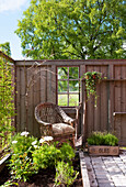 Wicker armchairs in front of wooden fence in garden