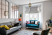 Large french metal salvaged windows in sitting room with grey vintage sofa, rug and small sofa upholstered