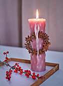 Rosa Kerze mit Sternanis-Kränzchen dekoriert