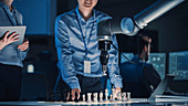 Engineer playing chess against a robotic arm