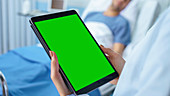 Doctor using a tablet with a green screen