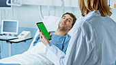 Doctor using a smartphone whilst talking to a patient