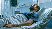 Ill man suffering while lying in a hospital bed