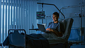 Recovering patient using a laptop in hospital