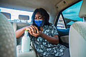 Woman using hand sanitiser in taxi