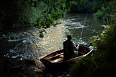 Man fly fishing from boat on river