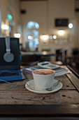Cappuccino on cafe table next to laptop