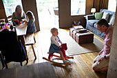 Family playing on rocking horse in cabin