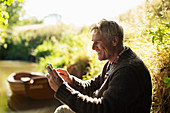 Man using smartphone at sunny riverbank