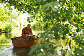 Man writing and fishing in boat on river