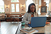 Woman working at laptop on table in cafe