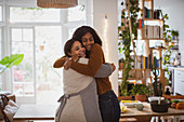 Happy mother and daughter hugging at home