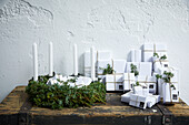 Weiß verpackte Geschenke als Adventskalender mit Wacholderwzeigen dekoriert und Adventskranz aus Wacholderzweigen
