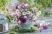 Bouquet of daisies, lilacs, roses, allium, columbines, caraway, and a grass wreath
