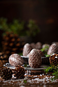 Festive pine cone shaped chocolates on a wire rack surrounded by fir sprigs and real pine cones