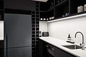 Fridge in black kitchen with white splashback