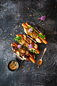 Vegetarian hot dogs in a pretzel bun with sweet mustard and chive flowers