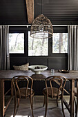 Wooden table with chairs in dining room with dark wall