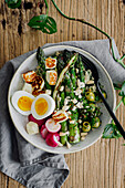 Summer lunch bowl with asparagus, radish, halloumi and egg