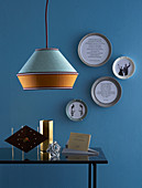 DIY picture frames made from plates, in the foreground a coffee table with decorative objects and a pendant lamp
