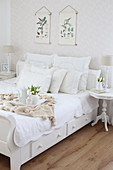 Weißes Bett mit Kissensammlung, Tablett und Tulpenstrauß