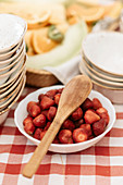 Wooden spoon on bowl of strawberries