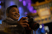 Happy young woman with camera in city at night