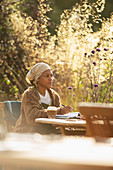 Woman with coffee working at sunny garden table