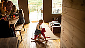 Girl playing on rocking horse in wood cabin