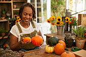 Female florist arranging autumn pumpkins in shop