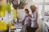 Mother and daughter doing dishes at kitchen sink