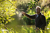 Man casting fly fishing pole into a river