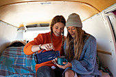 Young women friends enjoying coffee in camper van