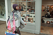 Young woman with shopping bags outside storefront