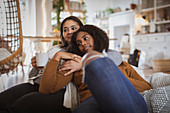 Mother and daughter cuddling on sofa