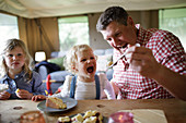 Father feeding cake to daughter