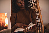 Young woman reading book in rattan chair