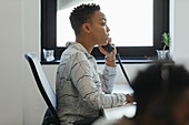 Businesswoman talking on telephone at office window