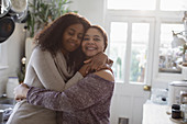Happy mother and daughter hugging in kitchen