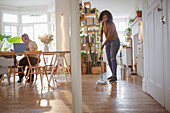 Women working and mopping hardwood floor in apartment