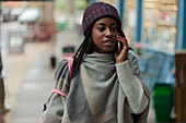 Young woman talking on smartphone on sidewalk